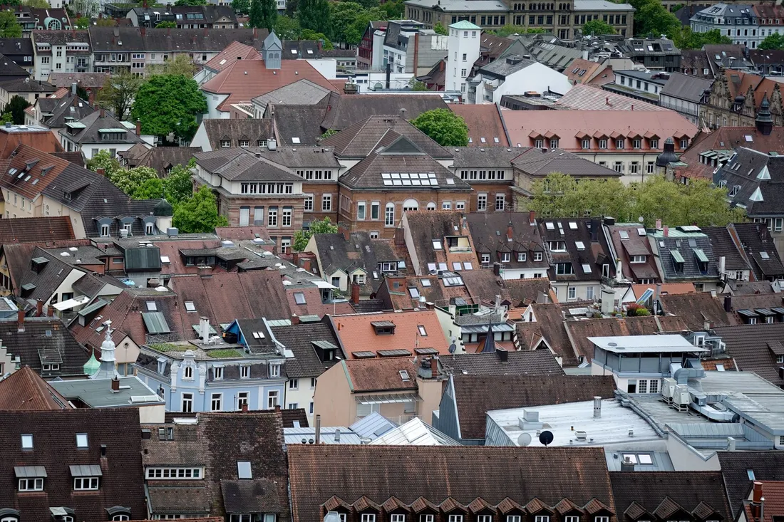 Blick von oben über die dicht gedrängten Ziegeldächer einer Altstadt, dazwischen ein Kirchturm.